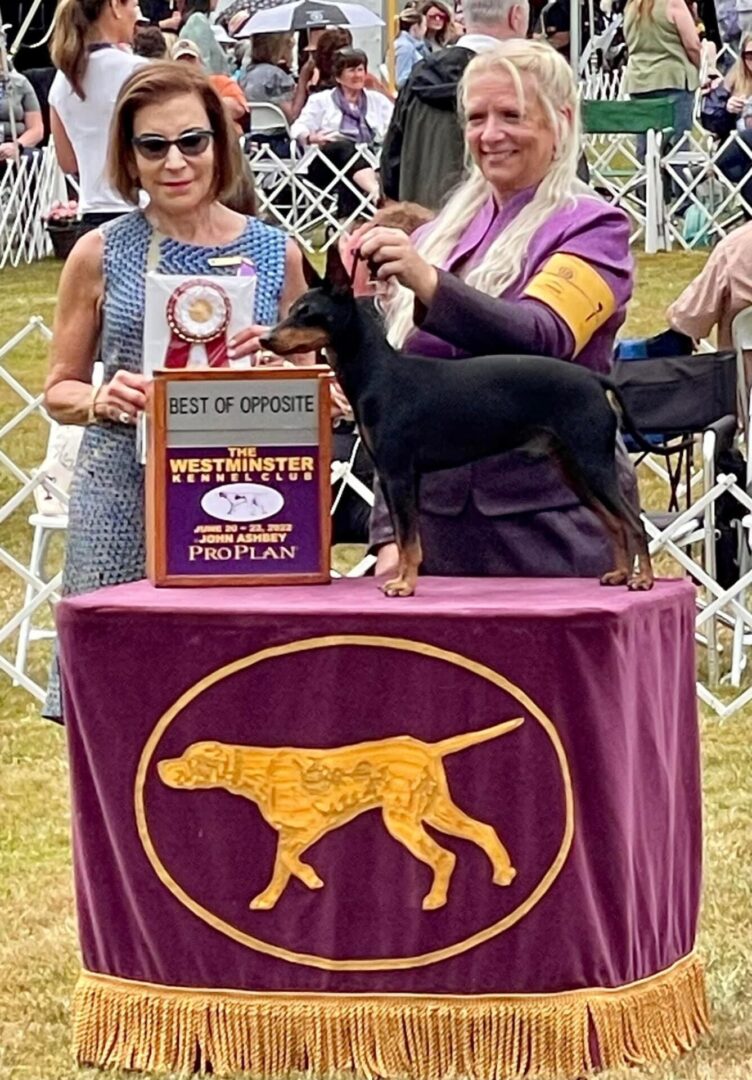 Two ladies posing with dog and awards