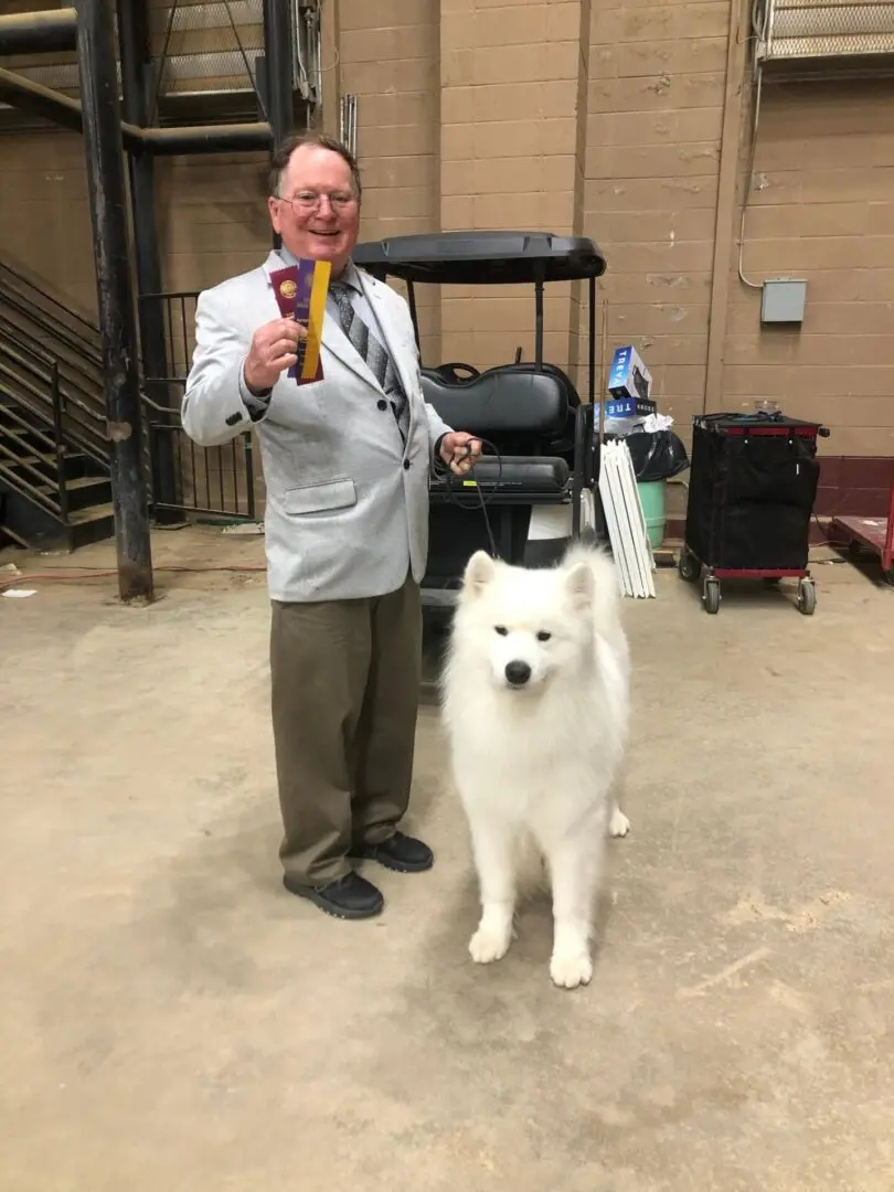 A man posing for a picture with his white dog